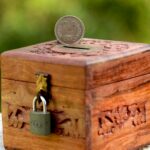 Wooden piggy bank with detailed carving and Indian coin, symbolizing savings and wealth.