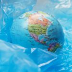A globe surrounded by blue plastic represents global environmental issues and pollution.